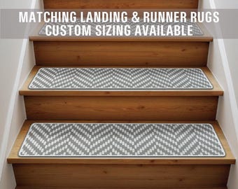 May include: A set of gray and white chevron patterned stair treads. The treads are placed on wooden stairs. The text "Matching Landing & Runner Rugs Custom Sizing Available" is displayed above the stairs.