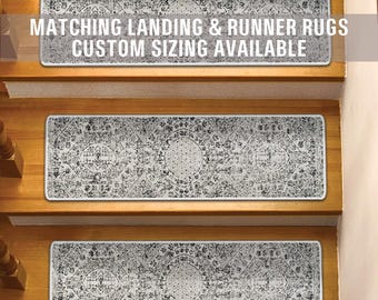 Op de afbeelding: Twee witte en grijze getrapte treden met een zwart-wit geometrisch ontwerp. De tekst "Matching Landing & Runner Rugs Custom Sizing Available" is gedrukt op de bovenste trede.