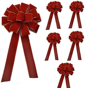 May include: Set of six red velvet bows with gold trim. The bows have two long tails and are perfect for decorating gifts, wreaths, or other holiday crafts.