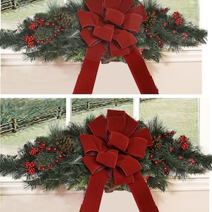 May include: A festive Christmas garland with lush green pine branches, red berries, and pine cones, adorned with a large, bright red velvet bow.