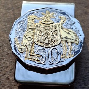 Sujetabilletes australiano con moneda de canguro y emú, sin circular, con estuche de regalo. Fabricado con plata .800 de 1966, con detalles en oro y plata, y diseño artístico.
