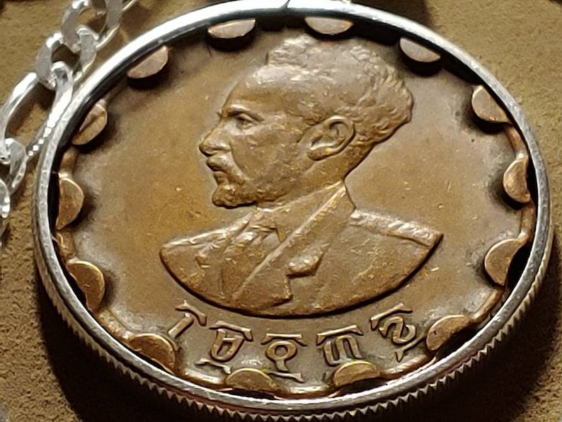 May include: A bronze coin with a portrait of a man with a beard and a crown. The coin has the text "I  ETHIOPIA" around the edge.