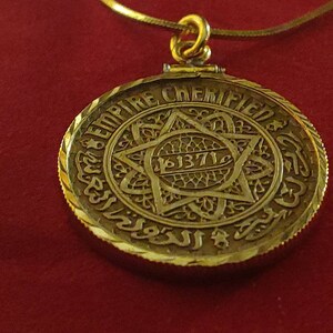 May include: A gold pendant necklace with a round, ornate pendant featuring a Star of David and the inscription "EMPIRE CHEMIFIED 1371".
