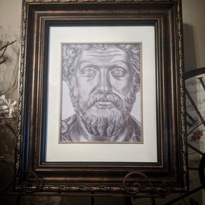 May include: A framed black and white pencil drawing of a man with a beard and a serious expression. The frame is brown with gold accents.