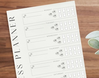May include: A fitness planner with the words "FITNESS PLANNER" printed vertically on the left side. The planner has sections for each day of the week, with spaces for notes, dumbbell icons, water glass icons, and exercise icons.