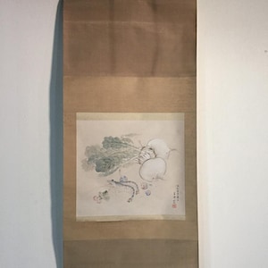 Może przedstawiać: Pionowe malowidło na zwoju z akwarelową ilustracją białych rzodkwi, zielonych warzyw liściastych i krewetek. Grafika osadzona jest na jasnobeżowym tle, z brązowym papierowym podkładem i drewnianym prętem na dole.