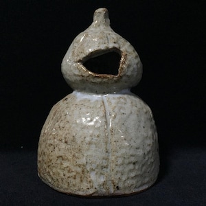 Può includere: Un recipiente in ceramica fatto a mano a forma di zucca, caratterizzato da una smaltatura testurizzata color bianco sporco con macchie marroni. L'oggetto presenta una base ampia e arrotondata e una parte superiore bulbosa con un'apertura.