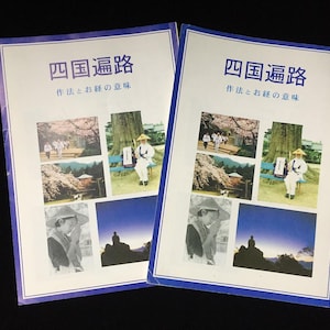 以下が含まれることがあります： 日本語の「四国遍路」というタイトルの2冊の日本の旅行ガイド。表紙には、人々、風景、伝統的な衣装を着た人物の複数の画像が掲載されています。ガイドには青い縁取りがあり、黒い背景にあります。