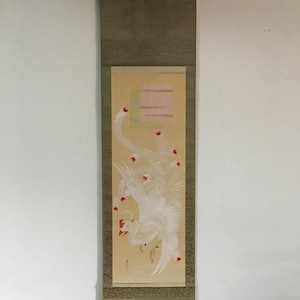 Puede incluir: Pintura tradicional japonesa en rollo que representa un ave blanca con detalles rojos sobre un fondo crema. La obra de arte incluye un diseño geométrico en rosa y verde, enmarcado por un borde verde apagado. El rollo está suspendido de un colgador metálico.