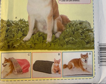 May include: Sewing pattern for a dog bed, featuring a brown and white dog, a cat, and a bed with a pink and brown blanket. The pattern includes instructions for sewing a circle to a straight edge, attaching hook and loop fasteners, and sewing with synthetic fur. The pattern is McCall's M7613.