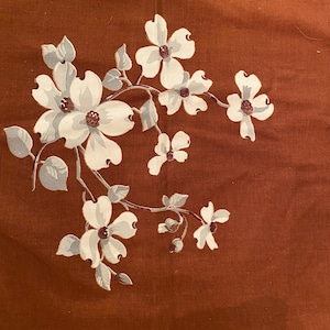 May include: A brown fabric with a white floral pattern. The flowers are stylized and have five petals. The fabric has a subtle texture.