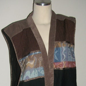May include: A brown and black patterned vest with a suede front panel. The vest has a V-neck and is sleeveless.