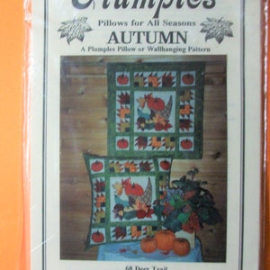 Könnte beinhalten: Ein Quiltmuster für ein Kissen oder eine Wandbehänge mit Herbstthema mit Kürbissen, Blättern und einem Füllhorn. Das Muster trägt den Titel "Plumples Pillows for All Seasons: Autumn".