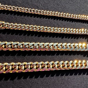 May include: Four gold-colored chain necklaces of varying lengths and widths. The chains are all made of a thick, chunky metal and have a classic curb link design.