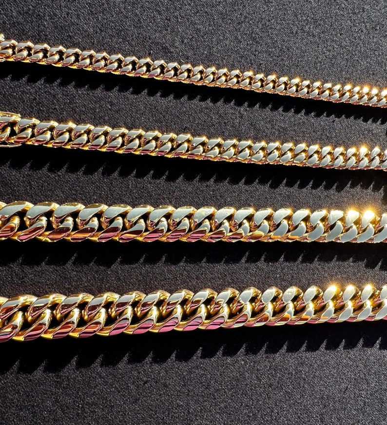 May include: Four gold-colored chain necklaces of varying lengths and widths. The chains are all made of a thick, chunky metal and have a classic curb link design.
