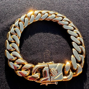 May include: A gold chain bracelet with a large, chunky link design. The bracelet has a secure clasp.