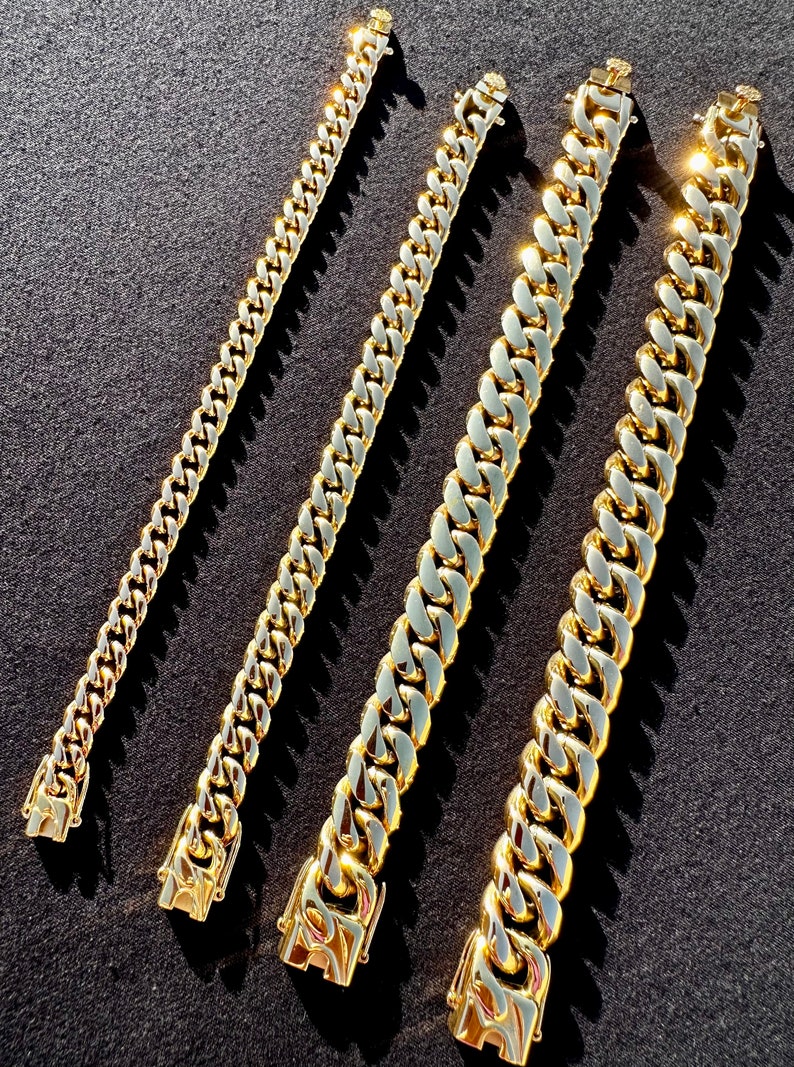 May include: Four gold chains of different lengths and widths. The chains are arranged in a row, with the shortest chain on the left and the longest chain on the right.