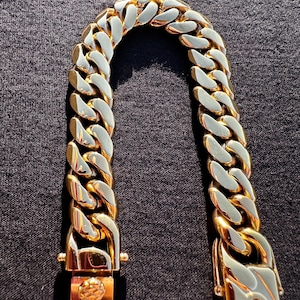 May include: A gold-toned chain bracelet with a curb link design. The bracelet has a clasp closure.