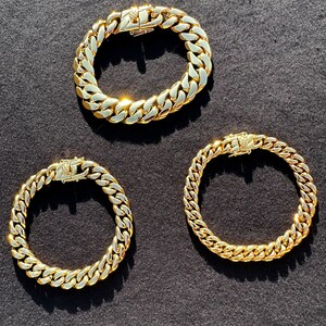 May include: Three gold chain bracelets on a black background. The chains are all the same style, but different lengths.