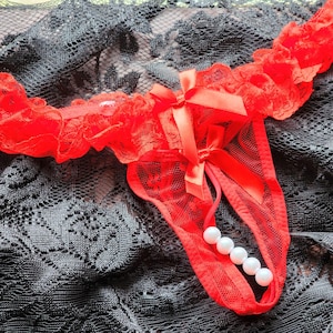 May include: Red lace lingerie with a bow and pearl accents.