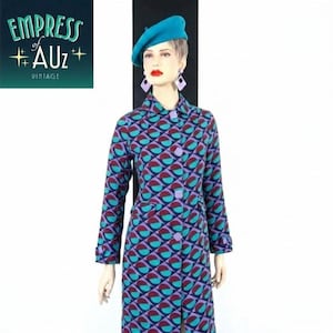 May include: A long-sleeved coat featuring a geometric pattern of teal and maroon semicircles on a dark purple background, with square buttons, worn with a teal beret and lavender geometric earrings. The logo Empress of AUz VINTAGE is visible.
