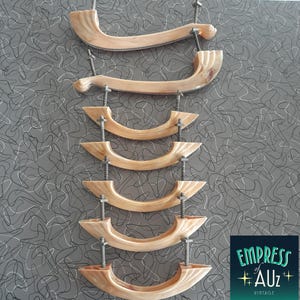 May include: A set of seven curved, light beige, marbled-effect drawer pulls with a smooth, glossy finish. Each handle features two threaded metal mounting bolts extending from the back, designed for attachment to furniture or cabinetry hardware.