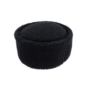 Könnte beinhalten: Ein schwarzer, runder, flauschiger Hut mit zylindrischer Krone und abgerundeter Oberseite. Der Hut besteht aus einem weichen, strukturierten Material und ist vor weißem Hintergrund platziert. Ein Winteraccessoire.