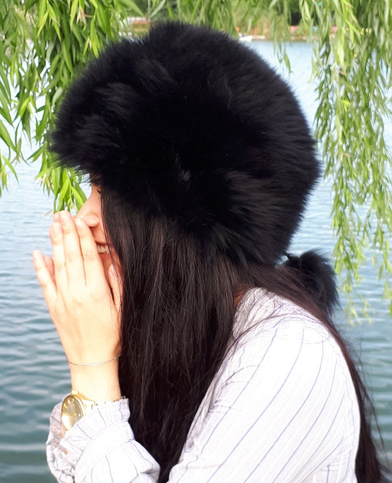 Peut inclure: Un chapeau en fausse fourrure noire, volumineux et arrondi, dot&eacute; d'une bande &eacute;paisse et textur&eacute;e. Le chapeau pr&eacute;sente un poil dense et doux qui recouvre toute la surface ext&eacute;rieure, offrant une silhouette pleine et arrondie sur la t&ecirc;te.