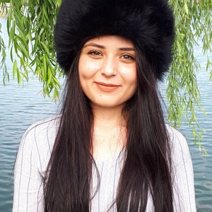 Peut inclure: Un chapeau en fausse fourrure noire, dense et duveteuse, de forme cylindrique arrondie. Cet accessoire pr&eacute;sente une texture &eacute;paisse et une couleur noire profonde, con&ccedil;u pour couvrir enti&egrave;rement le sommet de la t&ecirc;te avec une large bande structur&eacute;e.