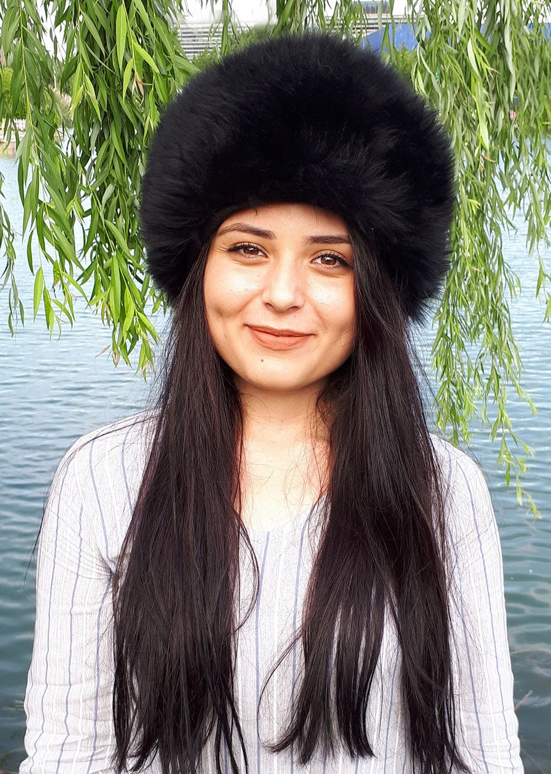 Peut inclure: Un chapeau en fausse fourrure noire, dense et duveteuse, de forme cylindrique arrondie. Cet accessoire pr&eacute;sente une texture &eacute;paisse et une couleur noire profonde, con&ccedil;u pour couvrir enti&egrave;rement le sommet de la t&ecirc;te avec une large bande structur&eacute;e.