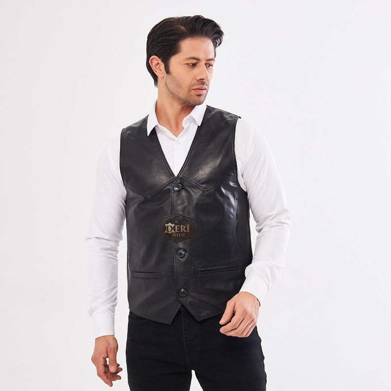 May include: A black leather vest featuring a V-neckline, three front buttons, and two side pockets. The vest displays a small, dark, shield-shaped logo on the chest with the text DERI SITESI printed in a light color on the center of the garment.