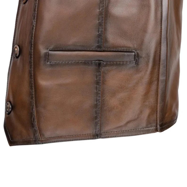 May include: A brown leather vest featuring a smooth finish with visible tonal variations. The garment includes a horizontal welt pocket on the front, vertical seam detailing with visible stitching, and two round brown buttons along the front edge.