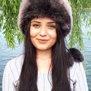 Peut inclure: Un bonnet en fausse fourrure gris fonc&eacute; avec un bord &eacute;pais et arrondi et une texture douce et pelucheuse. Le bonnet pr&eacute;sente un design circulaire qui se porte haut sur la t&ecirc;te, offrant une couverture compl&egrave;te avec un aspect dense et superpos&eacute;.