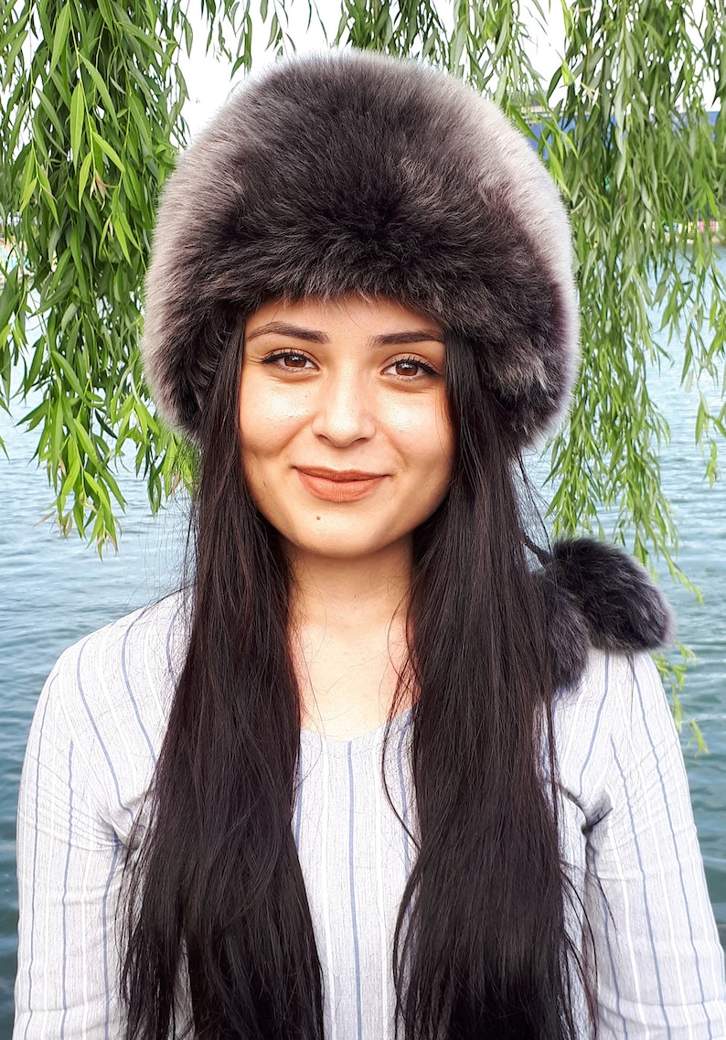 Peut inclure: Un bonnet en fausse fourrure gris fonc&eacute; avec un bord &eacute;pais et arrondi et une texture douce et pelucheuse. Le bonnet pr&eacute;sente un design circulaire qui se porte haut sur la t&ecirc;te, offrant une couverture compl&egrave;te avec un aspect dense et superpos&eacute;.