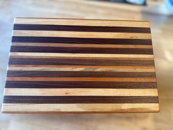 Custom edge-grain hardwood cutting board in walnut/cherry/ash — the kind of piece that gets passed down, not thrown out.