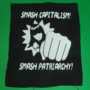 Könnte beinhalten: Schwarz-weißes Bügeleisen-Patch mit einem Cartoon-Bild einer Person mit einer erhobenen Faust. Der Text "Smash Capitalism!" und "Smash Patriarchy!" ist auf dem Patch aufgedruckt.