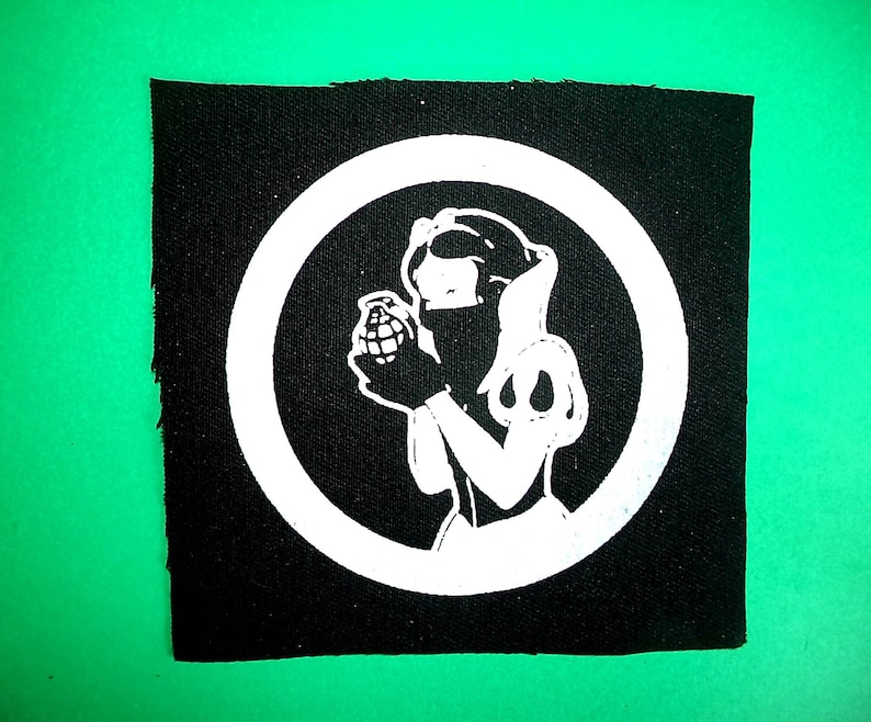 May include: Black and white iron-on patch featuring a stylized image of Snow White holding a grenade inside a white circle.