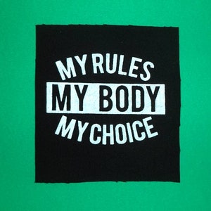 Puede incluir: Parche de tela negro con texto blanco que dice "My Rules My Body My Choice".