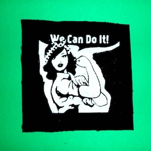 Peut inclure: Patch noir et blanc avec la silhouette d'une femme portant un bandana, fléchissant son biceps. Le texte "We Can Do It!" est au-dessus d'elle.