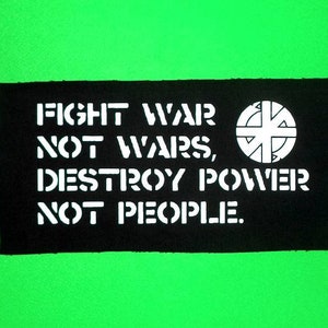 Könnte beinhalten: Schwarz-weißes Patch mit dem Text "Fight War Not Wars, Destroy Power Not People." und einem Kreis mit einem Kreuz darin.