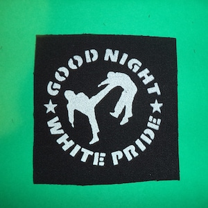 Könnte beinhalten: Ein schwarzer quadratischer Aufnäher mit weißem Text und einer Grafik von zwei Figuren in einer Kampfsportpose. Der Text lautet "GOOD NIGHT WHITE PRIDE" in einer kreisförmigen Anordnung.