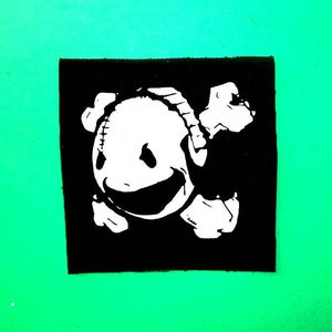 Puede incluir: Ilustración en blanco y negro de una calavera sonriente con una gran sonrisa y un hueso a cada lado de la cabeza.