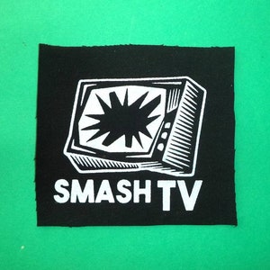 Peut inclure: Patch thermocollant noir et blanc avec un graphique d'un écran de télévision cassé et le texte "SMASH TV".