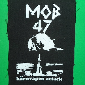 Op de afbeelding: Zwart-witte patch met de tekst "MOB 47 kärnvapen attack" in punkrock stijl.