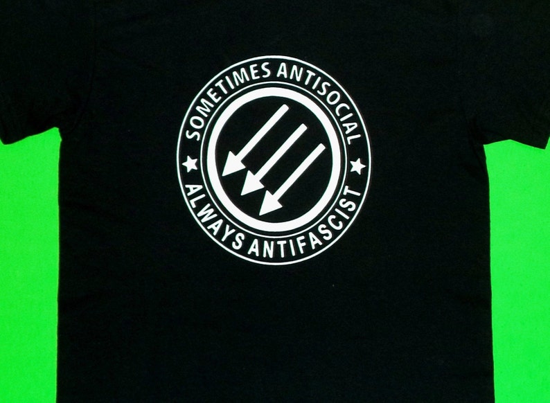 May include: Black t-shirt with a white circle graphic that says "Sometimes Antisocial Always Anti-Fascist" and features three white arrows pointing to the left.