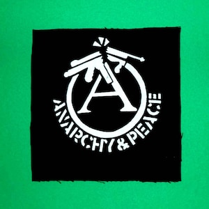 May include: Black and white patch with a circle containing the letter "A" and the words "Anarchy & Peace" around the circle. Three stylised guns are positioned above the circle.