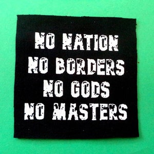 Könnte beinhalten: Schwarzer quadratischer Aufnäher mit weißem Text: "NO NATION NO BORDERS NO GODS NO MASTERS." Der Aufnäher befindet sich auf einem grünen Hintergrund. Der Text hat ein abgenutztes Aussehen.