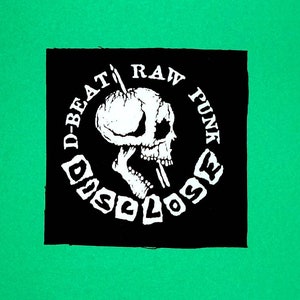 Könnte beinhalten: Schwarz-weißes Bügeleisen-Patch mit einem Totenkopf- und Knochen-Design. Der Text um den Schädel lautet "D-Beat Raw Punk Disclose".
