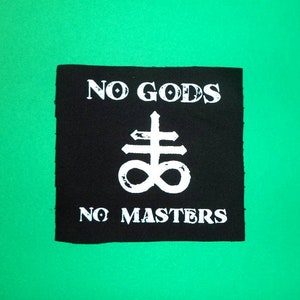 May include: Black and white patch with the text "NO GODS NO MASTERS" and a white symbol of a cross with a circle around it.