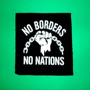 Pode incluir: Patch preto e branco com o texto "NO BORDERS NO NATIONS" e um punho cerrado quebrando uma corrente.
